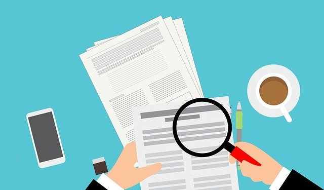 a person is holding a magnifying glass over a piece of paper